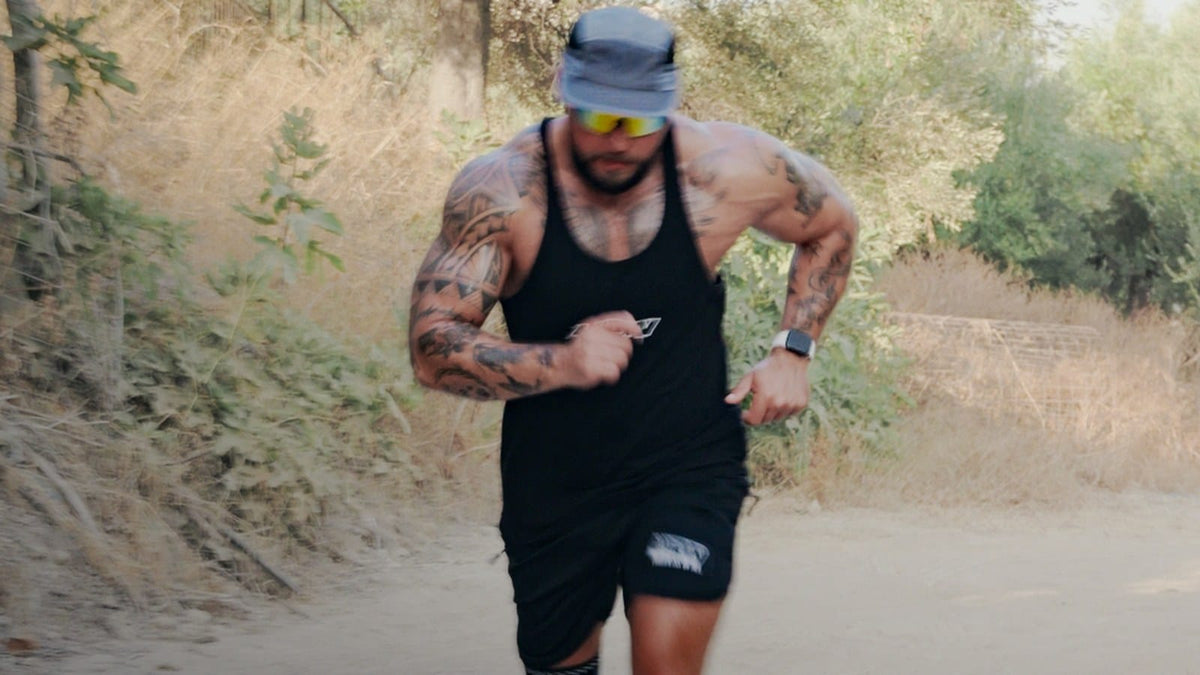Läufer in Sportkleidung joggt konzentriert einen sonnigen Feldweg entlang.